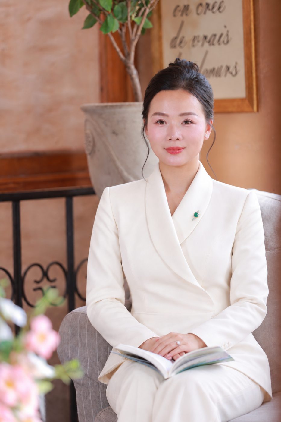 Elsa Phương trong bộ vest trắng, ngồi chính diện với cuốn sách