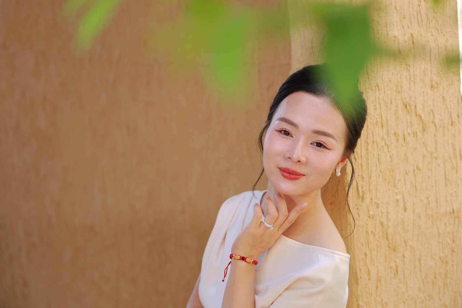 Elsa Phương tựa tường, nụ cười nhẹ nhàng, tay đặt dưới cằm